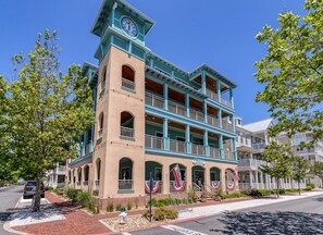 Un edificio de varios pisos con balcones, una torre de reloj y banderas estadounidenses.