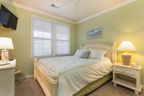 Un dormitorio con cama, mesitas de noche, televisión y ventana.