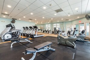 Un gimnasio con diversos equipos de ejercicio, como cintas de correr, bicicletas estáticas y máquinas de pesas.