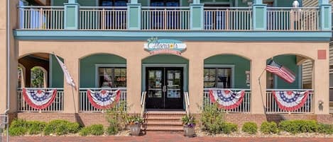 Edifici de dues plantes amb un balcó, un rètol que diu 'Marie's Market & Cafe' i banderes americanes a la façana.