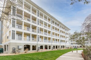 Un hotel de varios pisos con balcones, un paseo techado y una zona verde.