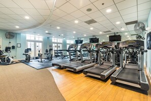 Un gimnasio con cintas de correr, bicicletas estáticas y máquinas de pesas.