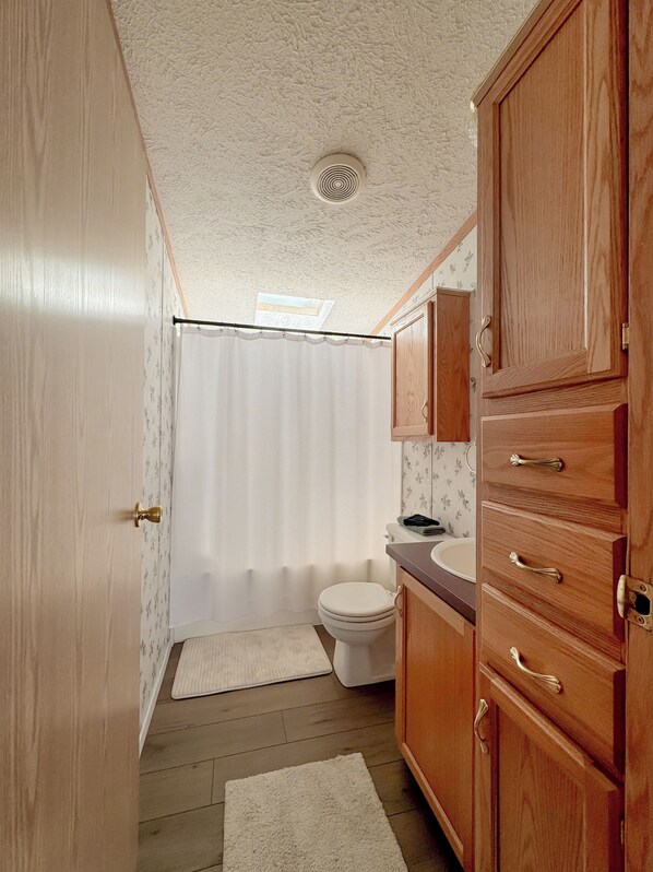 A compact bathroom with a toilet, sink, and wooden cabinets.