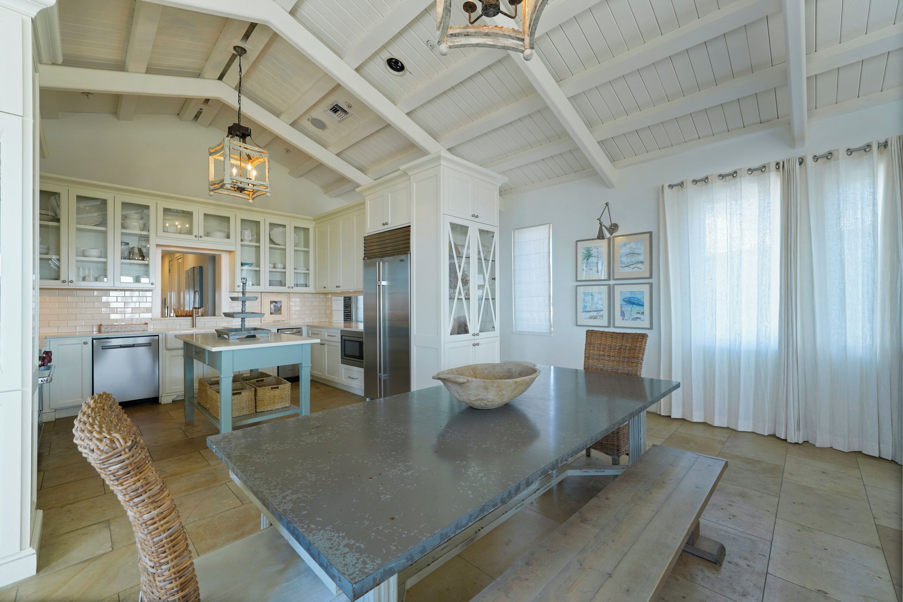 A spacious kitchen with white cabinetry, a large island, and a hanging light fixture.