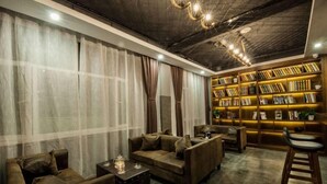 Un espace salon confortable avec des canapés en cuir, une table basse et une bibliothèque remplie de livres.