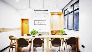 A conference room with a long table, four chairs, two potted plants, pendant lighting, a map on the wall, and a window with a view. - 7days Premium (Chongqing Tongliang Square) (Chongqing)