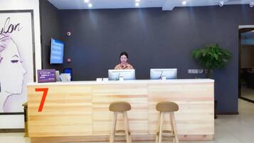 A reception desk with a number sign, a digital screen, and two stools.