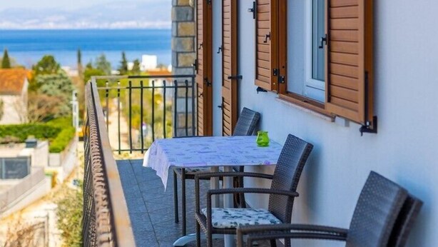 A balcony with a table and chairs, overlooking a scenic view.