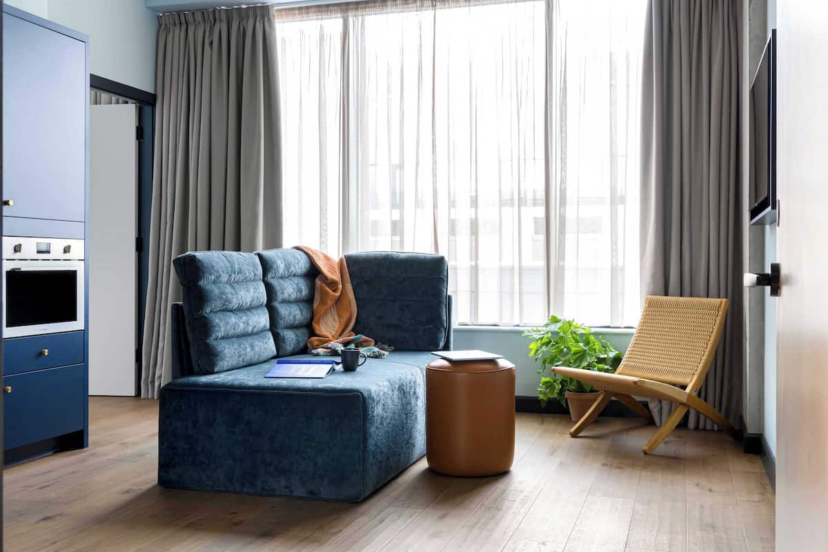 A modern living room with a sofa, ottoman, and a rattan chair.