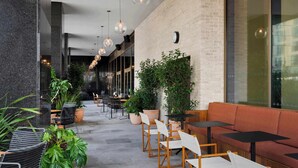 Un espacio exterior moderno con mesas, sillas y plantas en macetas.