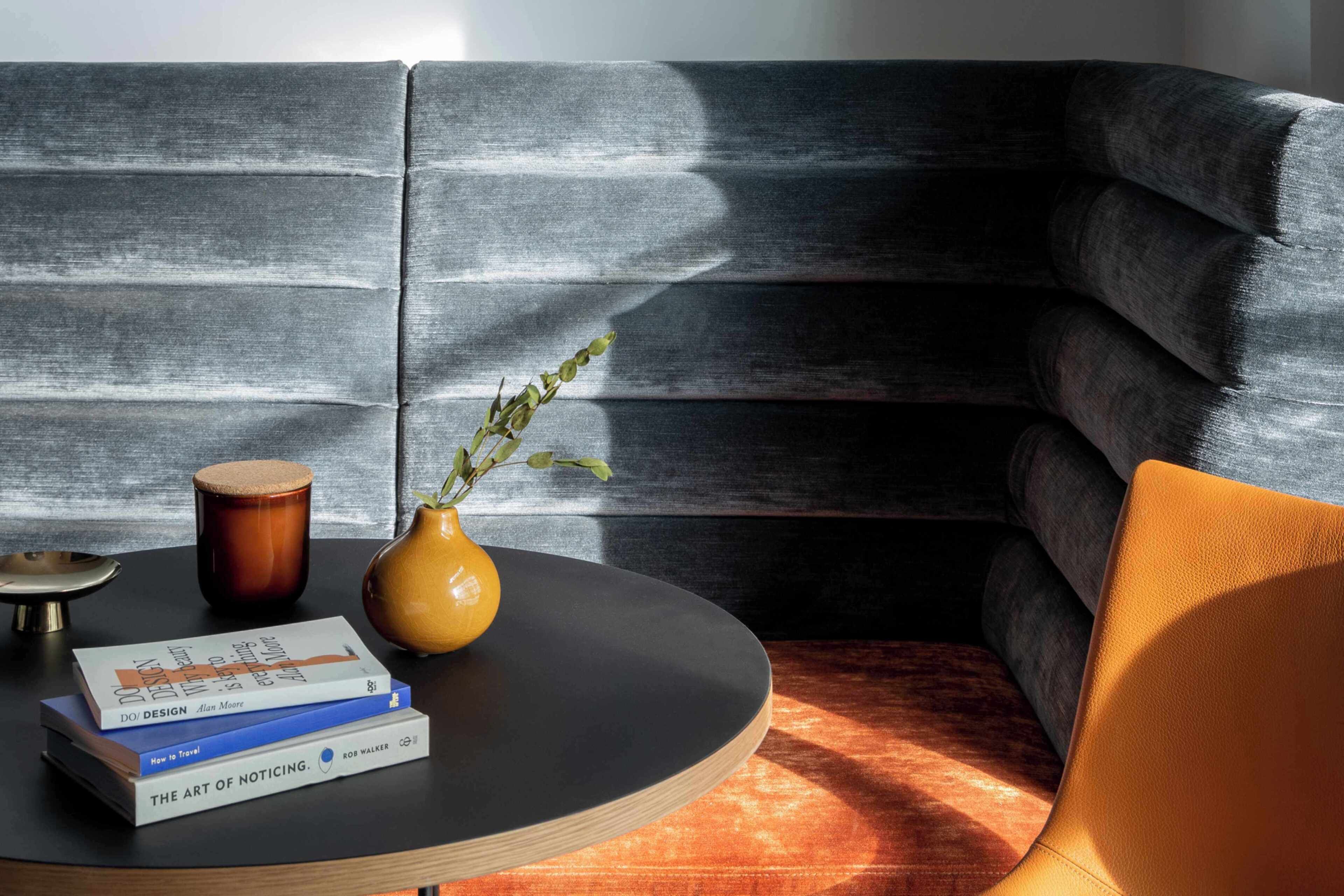 A modern living room with a black sofa, a round coffee table, and a few books.