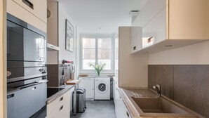 A modern kitchen with a built-in oven, a washing machine, and a sink. - Le Zénith - avec vue mer (Saint-Malo)