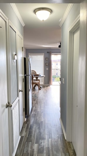 A hallway with a wooden floor, a ceiling light, and a door with a handle.