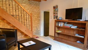 Un salon avec un escalier en bois, un canapé en cuir noir, une table basse noire, une bibliothèque en bois et un téléviseur à écran plat.