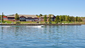 Un hôtel situé au bord de l’eau, composé de plusieurs bâtiments, avec un quai et un bateau à moteur amarré sur l’eau.