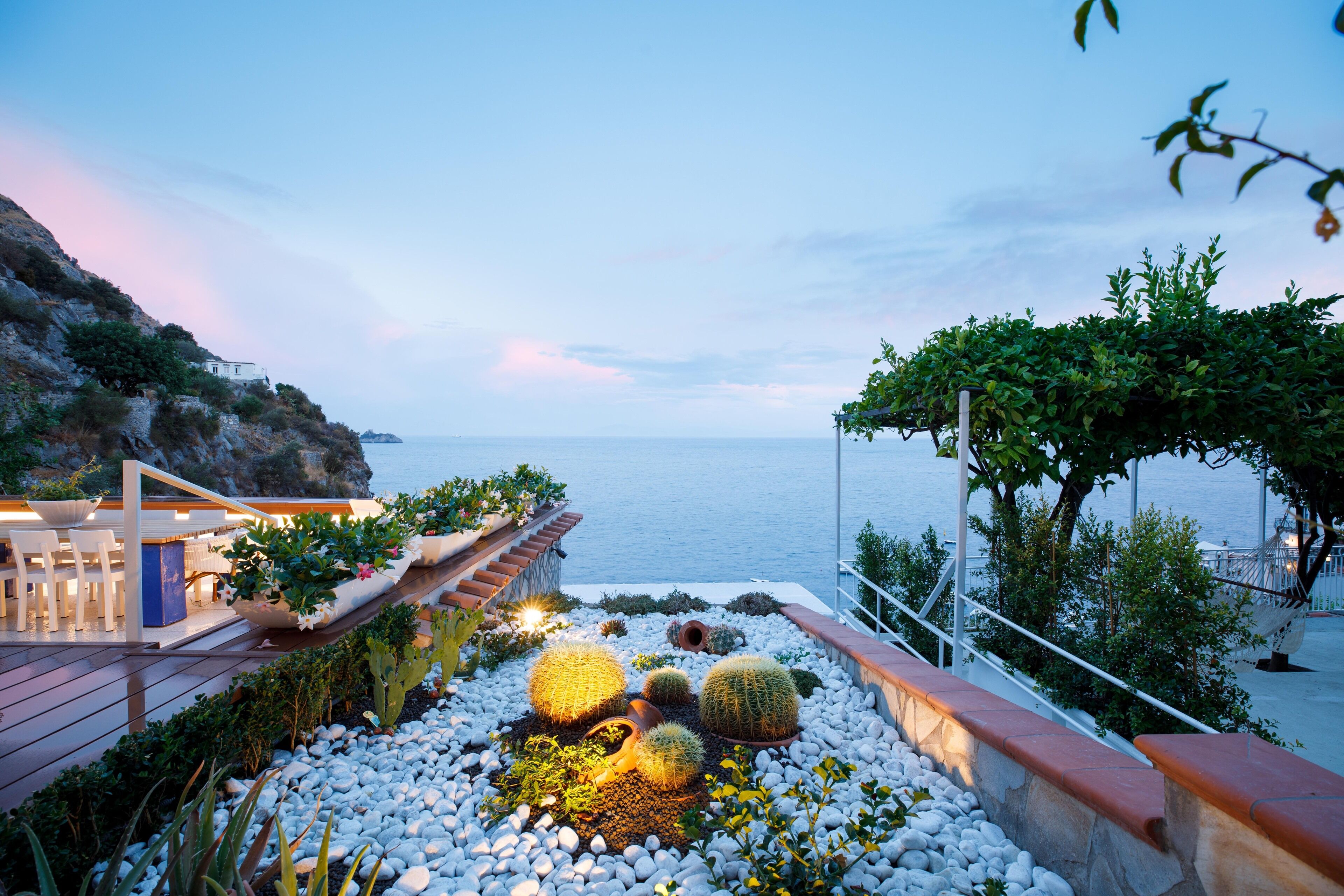 A coastal property with a patio area featuring cacti and a view of the sea.