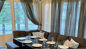 Un comedor con una mesa negra preparada para cuatro personas, un sofá oscuro y un banco.