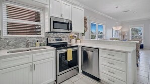 A modern kitchen with white cabinetry, stainless steel appliances, and a large island. - Swell Life | Walk to Beach | Large Pool | Near 30A & Pier Park | Sleeps 12 (Panama City Beach)