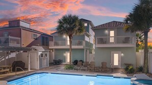A swimming pool with lounge chairs, a barbecue area, and a covered patio with outdoor furniture. - Swell Life | Walk to Beach | Large Pool | Near 30A & Pier Park | Sleeps 12 (Panama City Beach)