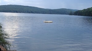 A calm lake with a small boat in the center, surrounded by forested hills. - Private lakeside cabin for those looking for peace and quiet in Brant Lake. (Brant Lake)