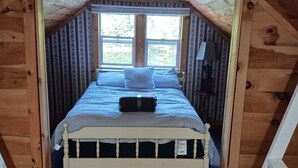 A small, cozy attic bedroom with a wooden sloped ceiling, a single bed with a white frame, and a window providing natural light. - Private lakeside cabin for those looking for peace and quiet in Brant Lake. (Brant Lake)