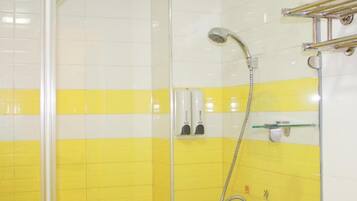 A bathroom with yellow and white tiles, a glass shower enclosure, a handheld showerhead, and a towel rack.