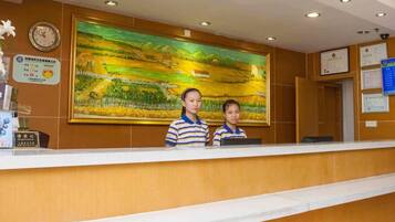 A reception desk with a large landscape painting above it, a clock, and various certificates on the wall.