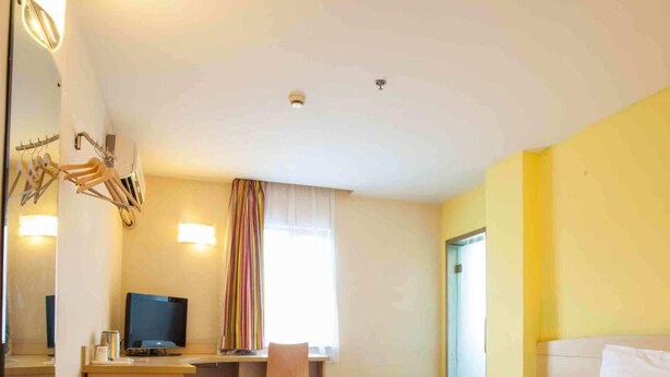 A hotel room with a bed, a desk with a chair, a television, and a window with curtains. - 7 Days inn Chongqing (Chongqing)