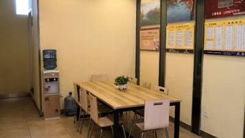 A dining area with a wooden table, chairs, a water dispenser, and a potted plant.