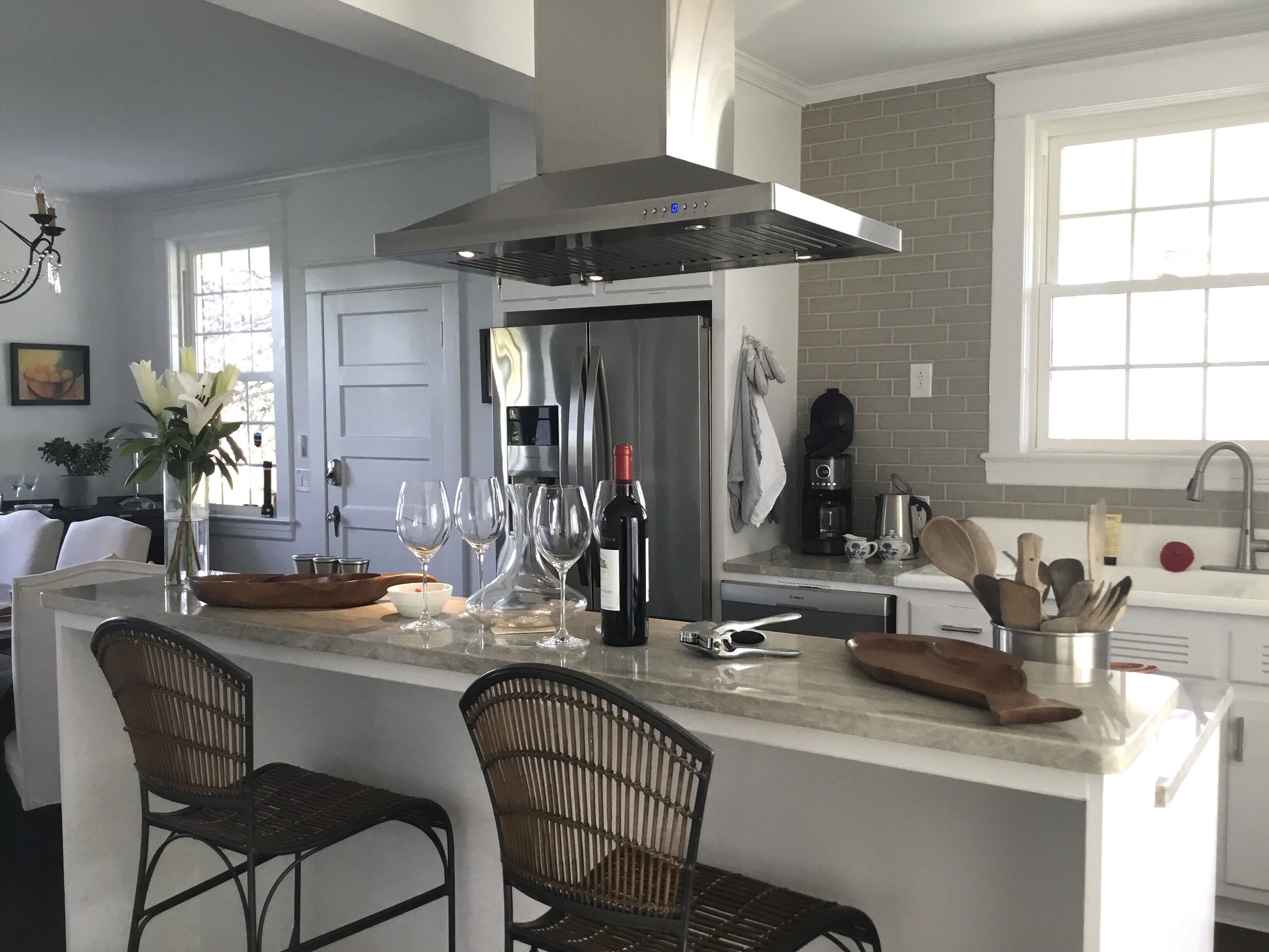 A modern kitchen with a central island, stainless steel appliances, and a brick backsplash.