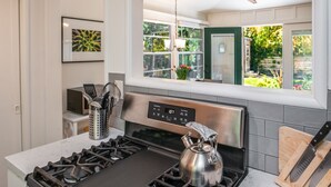 Cocina moderna con estufa de acero inoxidable, hervidor y bloque de cuchillos sobre la encimera.
