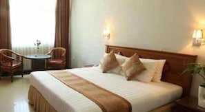 A hotel room with a bed, bedside tables, a chair, and a small table.