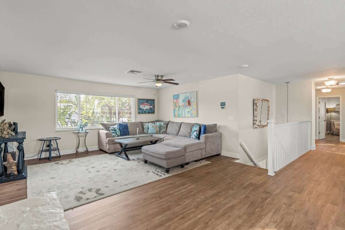 A living room with a sectional sofa, a coffee table, a fireplace, and a large window with blinds.