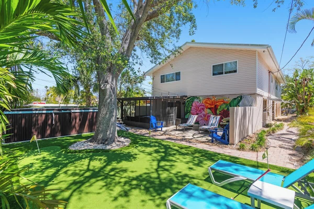 A house with a backyard, a tree, and a pool area.