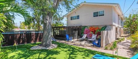 A house with a backyard, a tree, and a pool area.