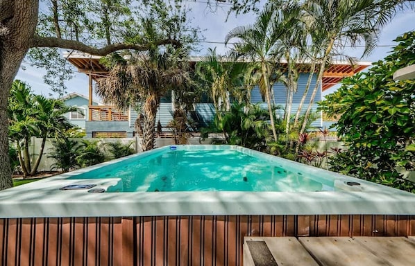 A hot tub surrounded by tropical plants and a building with a blue roof.