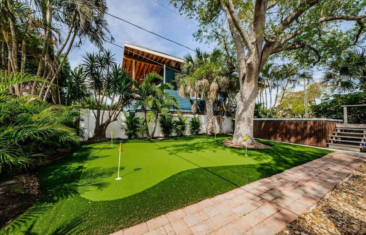 A residential property with a well-maintained lawn, a wooden deck, and a large tree.