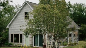 A small, single-story house with a gabled roof, a front door, and a window. - The Acadia Gateway House (Trenton)