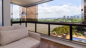 Ein Balkon mit einer Couch, einer Lampe und Blick auf eine Stadtlandschaft und Wasser.