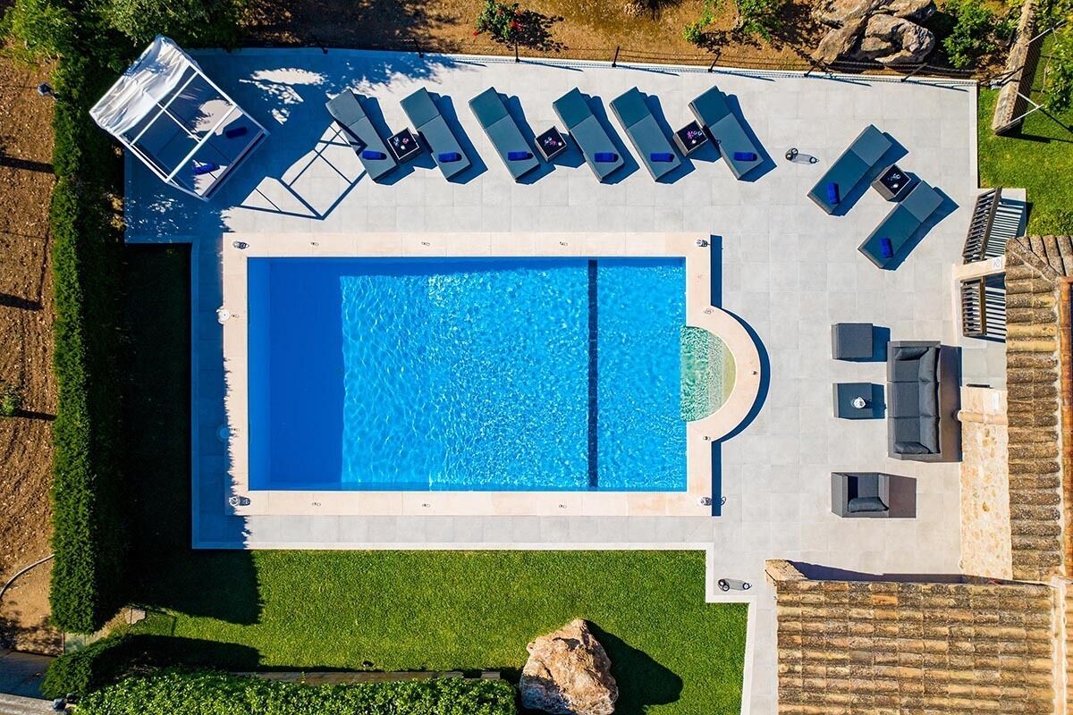 An aerial view of a swimming pool area with lounge chairs and a hot tub.