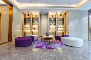 A modern lobby with seating areas, a central round table, and shelves with products. - Lavande Hotel (Chongqing)