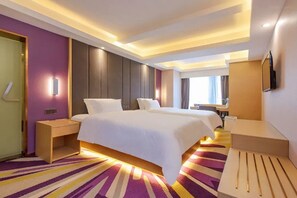 Une chambre d’hôtel dotée d’un grand lit, de tables de chevet, d’un téléviseur à écran plat et d’une salle de bain avec douche et toilettes.