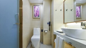 A modern bathroom with a toilet, a sink, a mirror, and a shower area. - Lavande Hotel (Chongqing)