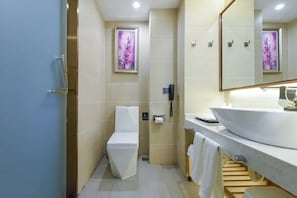 Une salle de bain moderne comprenant des toilettes, un lavabo, un miroir et un espace douche.