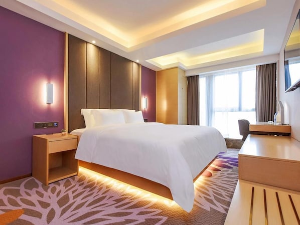 Une chambre d’hôtel avec un grand lit, des tables de chevet, un bureau, une chaise et un téléviseur.