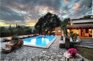 A pool area with stone flooring, lounge chairs, and a view of the mountains. - Villa Encinas, Spectacular recently renovated villa (Pollença)