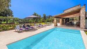 Une piscine avec des chaises longues, un patio couvert et une vue sur le paysage environnant.