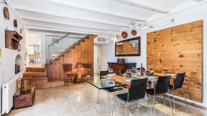 Un vaste espace dédié à la salle à manger, agrémenté d’un escalier en bois menant à un niveau supérieur, d’un grand miroir et d’un mur en bois rustique.