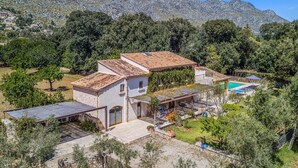 Une villa avec piscine, entourée d’arbres et de montagnes.