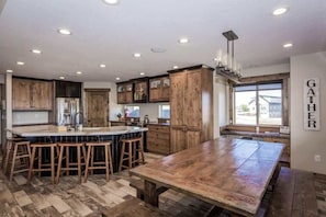 Une cuisine spacieuse avec des meubles en bois, un grand îlot central doté de tabourets et une vue sur l’extérieur grâce à une fenêtre.